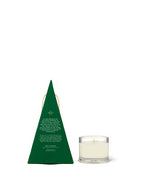 The image shows a candle in a clear glass holder next to its packaging. The packaging is shaped like a green triangle, resembling a stylized Christmas tree.