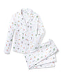 White pajama set featuring a button-up top with a collar, long sleeves, and a left chest pocket, paired with matching pants with an elastic waistband. The fabric is adorned with colorful, whimsical illustrations of animals and people engaged in various activities.