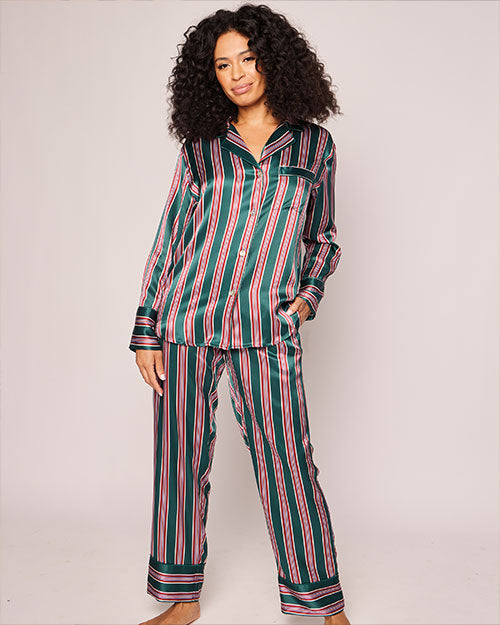 A person standing against a plain background, wearing a striped pajama set. The pajama set includes a long-sleeved button-up shirt and matching pants, both featuring vertical stripes in colors of green, and red.