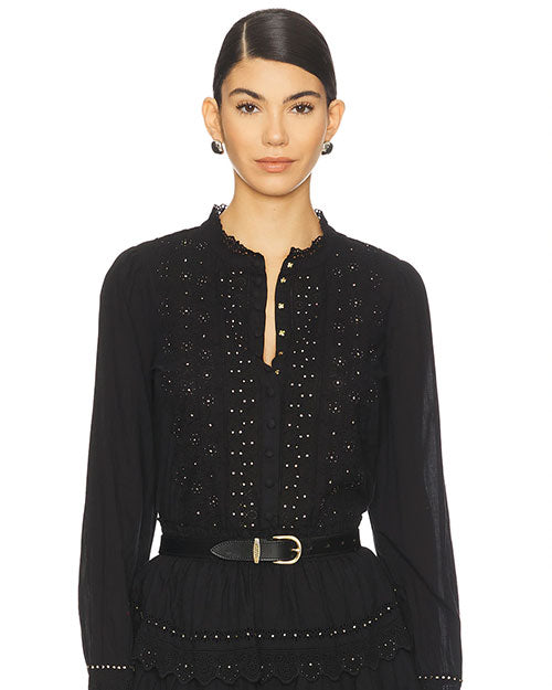 Front view of a black long-sleeve blouse featuring a scalloped neckline, button-down front, intricate eyelet embroidery with small stud embellishments, and a black belt with a gold buckle at the waist.