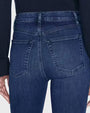 The back view of a pair of blue denim jeans, focusing on the waistband, pockets, and seams. The jeans feature two stitched back pockets with a center seam running down each. 