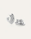 Pair of silver hoop earrings with a modern, layered, and curved design; smooth reflective surface, one earring upright and the other lying on its side.