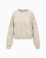Light gray sweatshirt with long sleeves and a crew neckline, featuring multiple bow-shaped cut-out designs across the front and sleeves, revealing a lighter lace underneath for contrast.
