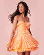 Model wearing a bright orange dress with ruffled details on the top and bottom, standing against a plain background.