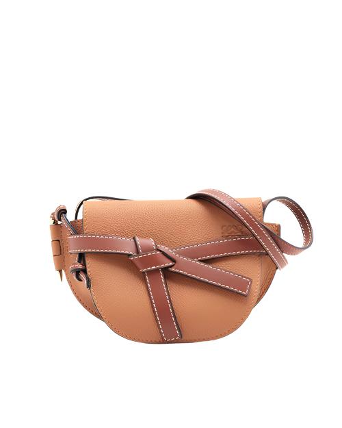 A Loewe tan leather crossbody bag with a distinctive bow-shaped belt closure, featuring visible white stitching against the tan leather, and a long strap.