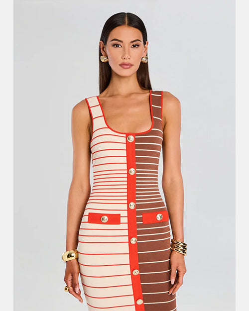 A frontal view of a model wearing an over the shoulder straps, just below knee-length dress with a fitted silhouette. The dress is half white/cream and half brown and features horizontal stripes in varying shades of red and white, with a vertical red stripe running down the center front. The red stripe is adorned with medium sized buttons. Additionally, the person has gold bracelets on both wrists and gold hoop earrings. 