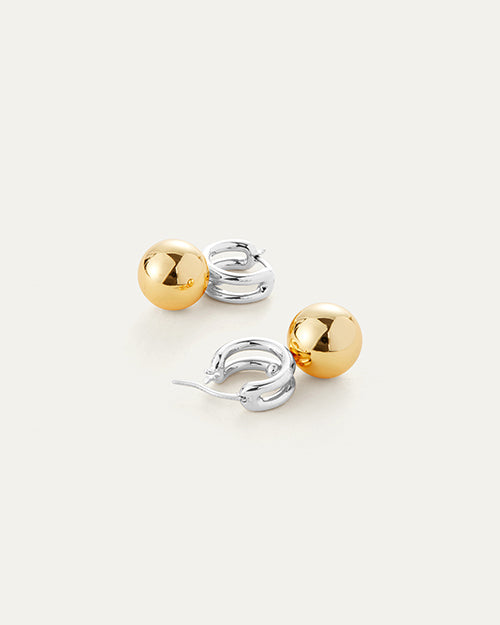 A pair of earrings featuring a two-tone design. Each earring consists of a small silver hoop connected to a larger, polished gold sphere. Earrings have a clasp design.