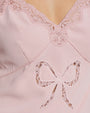 Close-up of a pink garment with lace detailing and a bow.