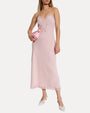 Woman wearing a pink slip dress holding a clutch on a white background