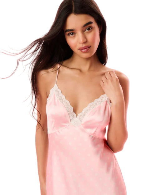 Woman wearing a pink satin dress with lace trim on a pink background