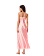 Person standing with their back to the camera, wearing a long pink satin slip dress with thin straps and lace trim, paired with flat sandals.