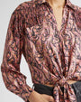 Patterned blouse with long sleeves and a tied front on a plain background