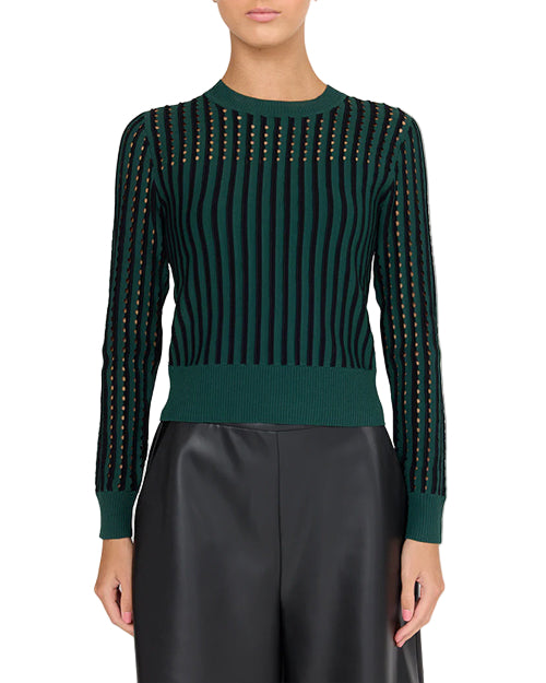 A person wearing a green and black vertically striped sweater with long sleeves. The sweater has ribbed cuffs, hem, and neckline. The person is also wearing shiny black pants.