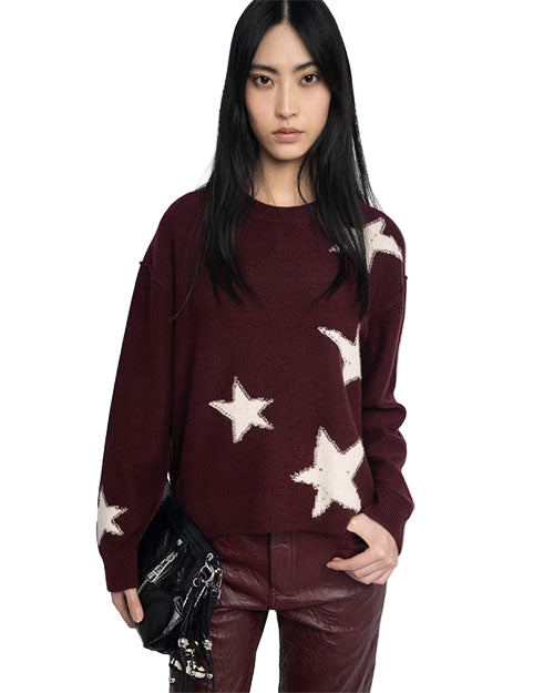 Person wearing a maroon sweater with white star patterns and matching maroon pants, holding a black handbag in the left hand.