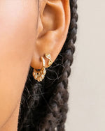 Close-up of a person’s ear wearing two hoop earrings.