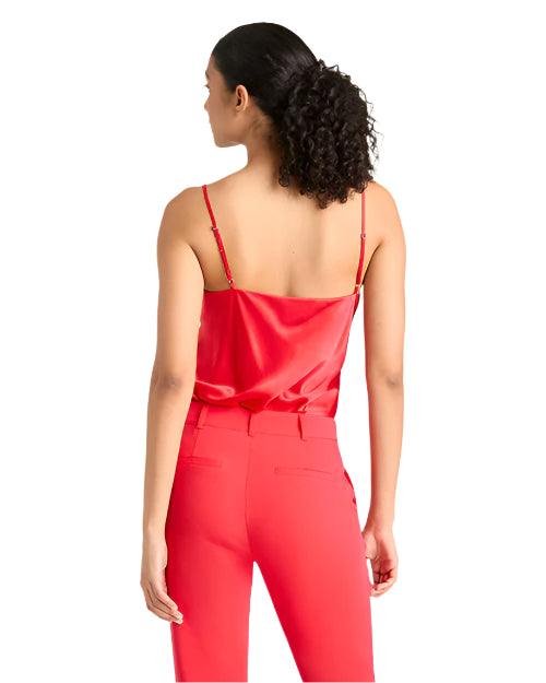 Back view of a woman wearing a red silk top tucked in and red pants on a light background