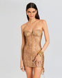 A close up of a tan lace mini dress. The dress features a strapless, sweetheart corset bodice with boning detail throughout. The dress has oversized ties at each side, with a classy sheer design.