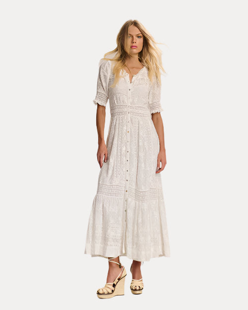 Front view of a woman wearing a white lace dress  with wedges against a plain background