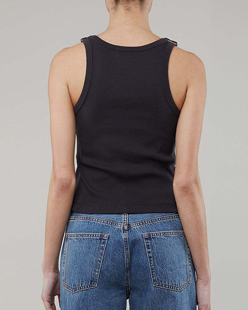 The backside view of a person wearing a navy tank top with adjustable buckle straps and blue jeans.