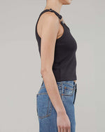 The side view of a person wearing a navy tank top with adjustable buckle straps and blue jeans.