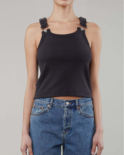 A person wearing a slightly cropped navy tank top with adjustable buckle straps and blue jeans.