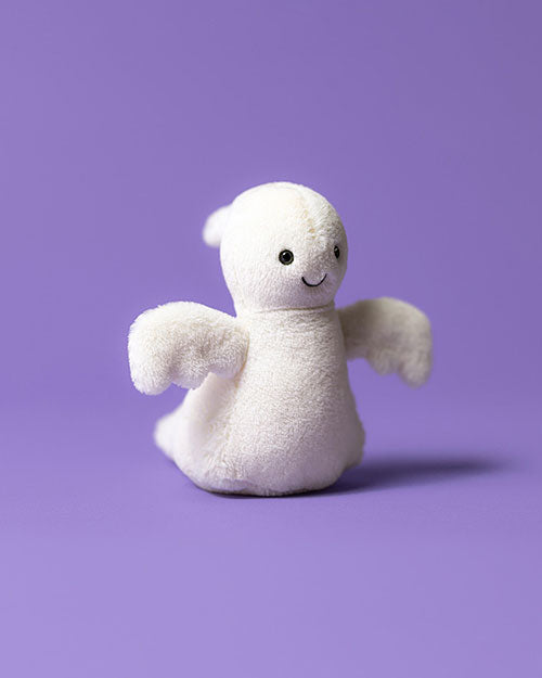 Small white plush toy with a smiling face and outstretched arms, set against a solid purple background.