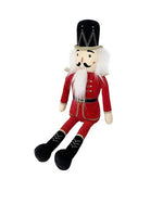 A traditional nutcracker doll with a black hat, white hair, mustache, and beard. It wears a red and gold uniform and black boots, sitting upright.