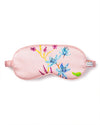 A pink sleeping mask featuring blue, yellow, and pink flowers. The mask has a ruched elastic band for securing around the head and a small tag that says 'PETITE'.  