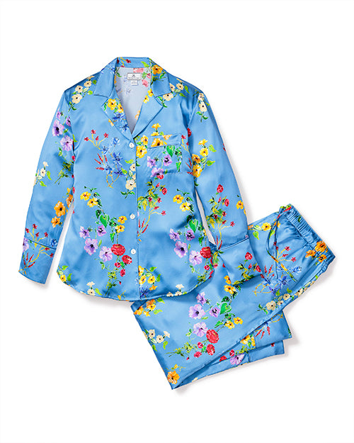 A satin blue pajama set with flowers in shades of pink, yellow, green, and red. The top is a button-up with a notched collar, and the matching pants have an elastic waistband and tie. 