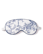A white and blue floral-patterned sleeping mask. The mask has an adjustable white strap for size adjustment. A small label with the text ‘PETITE’ is visible on the side.