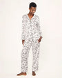 Person wearing a white pajama set with black piping and an all-over print of various buildings and landmarks. The set includes a long-sleeved, collared, button-down top and full-length, relaxed-fit pants.
