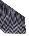 A close-up image of the tip of a necktie with an intricate black and white zigzag pattern displayed against a plain white background.