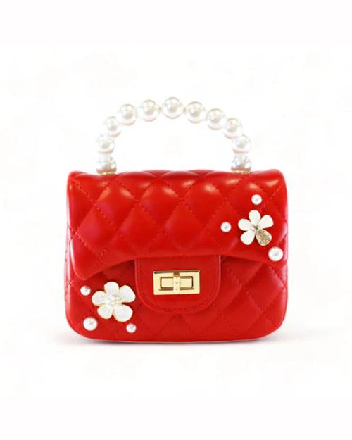 A small, red quilted handbag with a pearl handle. The bag features a gold clasp in the center and is adorned with white flower appliques, each with a gold center, distributed evenly.
