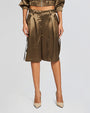 A close up of a pair of high-waisted, olive green satin shorts with a tie-up belt and large pockets on each side. The shorts have a wide leg design and reach just above the knee. They are paired with beige high-heeled shoes and a matching satin jacket.