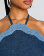 Close-up of a person wearing a blue denim halter top with a neutral background