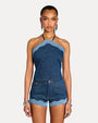 Woman wearing a denim halter top and shorts on a light gray background