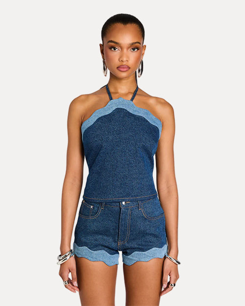 Woman wearing a denim halter top and shorts on a light gray background