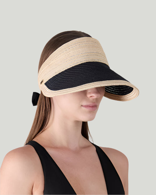 Woman wearing a beige and black visor against a gray background