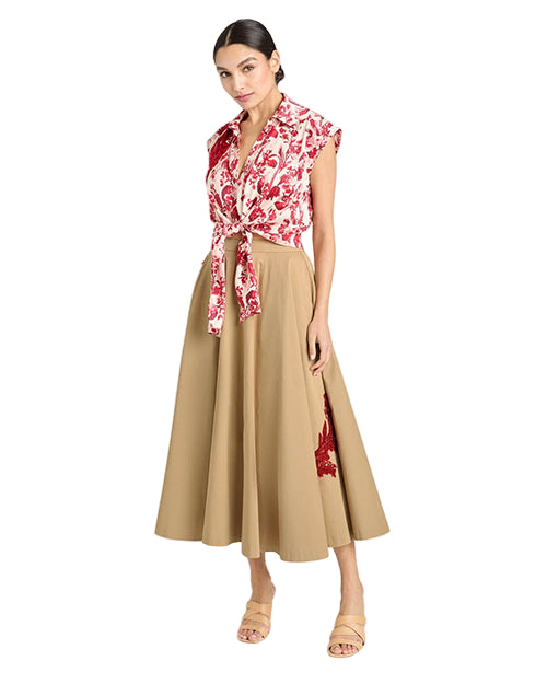 Woman wearing a floral top and beige skirt with red accents on a white background