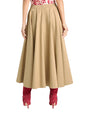 Back view of a person wearing a beige skirt  and red boots on a white background