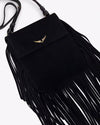 A close-up overhead view of a black handbag with one long strap and gold hardware, including tassels at the bottom and sides, and a gold wing design adorned at the top center.