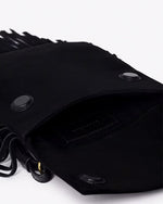 A close-up view of a black with an open flap featuring two snap buttons for closure. The interior of the bag is visible, showing an inner pocket, and fringes are visible along the sides and at the bottom. The background is plain white.