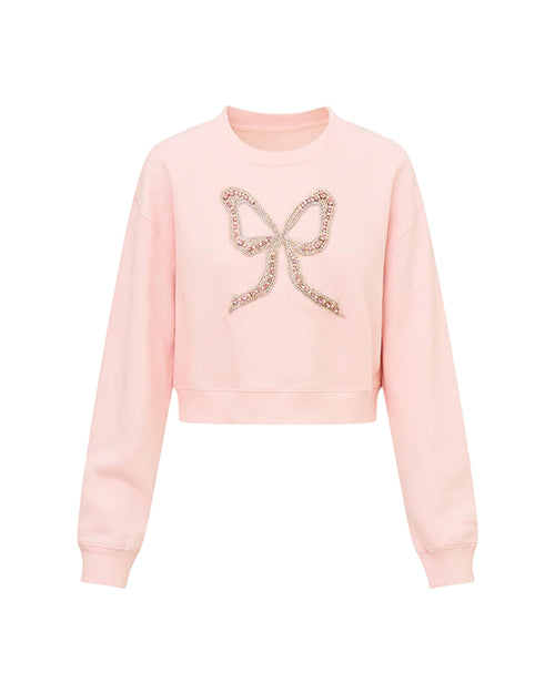 Light pink cropped sweatshirt with long sleeves, featuring a decorative bow design made of small, shiny embellishments on the front center.