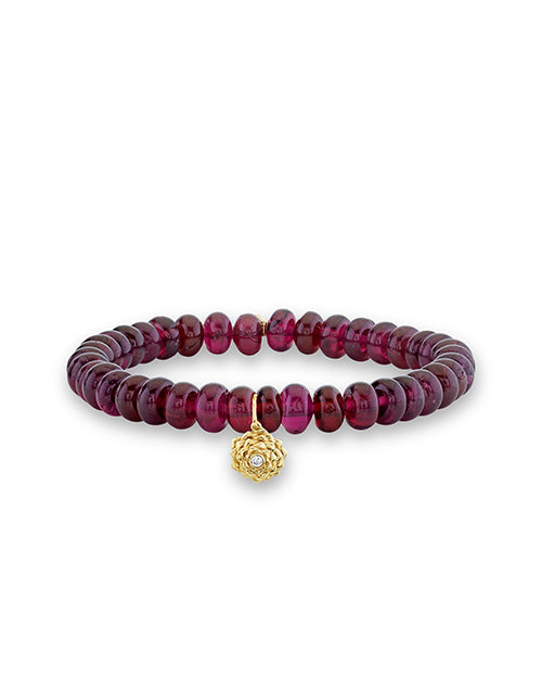 14k yellow gold and diamond small camellia charm on 7mm rhodolite beads on white background.