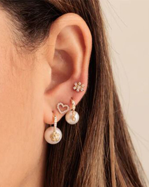 Close up on model's ear wearing heart earring with 3 other earrings to show versatility. 