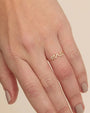 A close-up image of a hand with a ring on the ring finger. A gold ring with 'mrs' script embellished with pave diamonds.