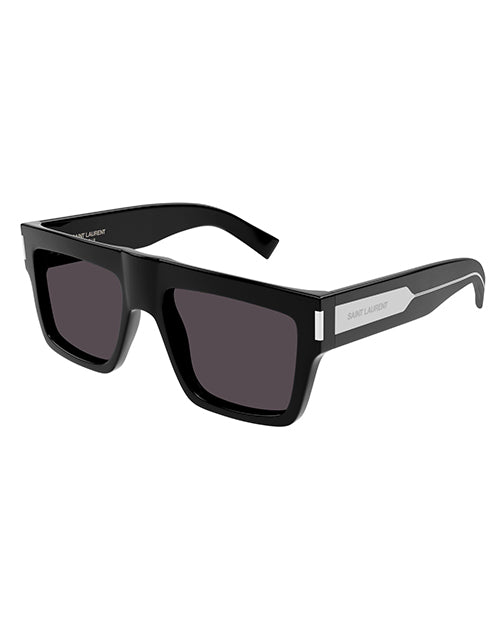A pair of black Saint Laurent sunglasses with a thick frame and large, dark lenses. The brand name ‘SAINT LAURENT’ is prominently displayed in engraved capital letters on the sides of the frame. The design is sleek and modern, suggesting a fashionable accessory.