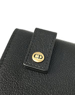 A close up of the back of a Christian Dior bag showing "CD" on the  loops where the strap goes through.