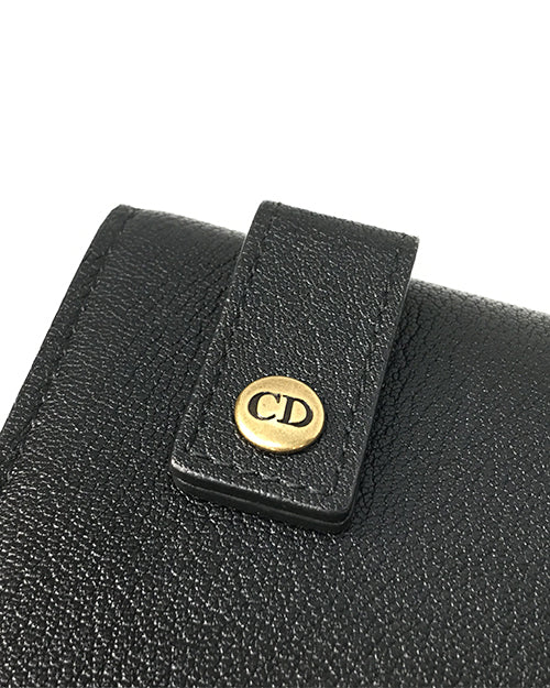 A close up of the back of a Christian Dior bag showing "CD" on the  loops where the strap goes through.