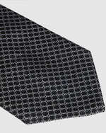 A close-up of a necktie with a black and gray geometric pattern.